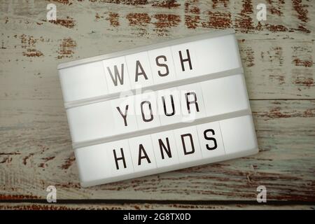 Wash Your Hands word in light box with space coy on white brick and wooden shelves background Stock Photo