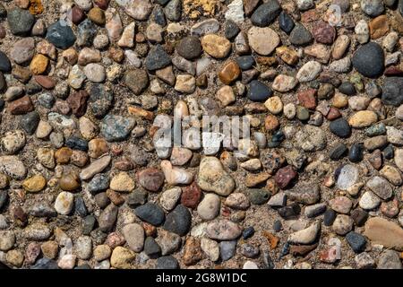 Top view close-up texture background of a vintage exposed aggregate stone patio surface in bright natural sunlight Stock Photo