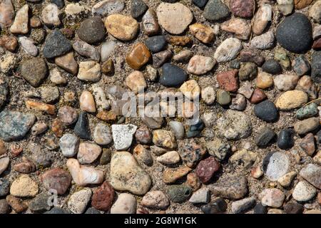 Top view close-up texture background of a vintage exposed aggregate stone patio surface in bright natural sunlight Stock Photo