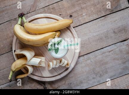 Summer flatlay with banana smoothie or milkshake, mint leaves and straw in a glass on dark wooden table Stock Photo