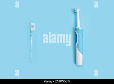 Traditional Manual and Electric Toothbrush Over Blue. choice between electric and classic toothbrush on blue background. Manual Regular Toothbrush Aga Stock Photo