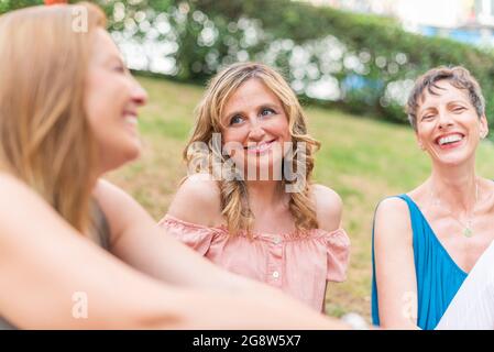 Close up view of three adult women sitting in the park laughing Stock Photo