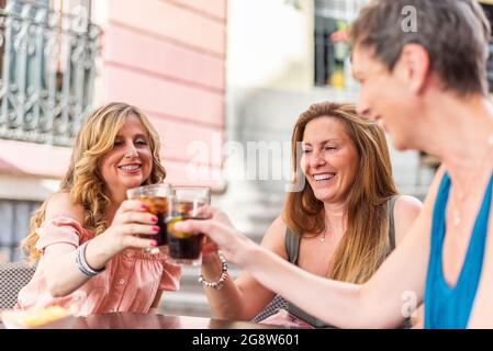 Middle aged adult women in a cafe toasting with drinks outside Stock Photo