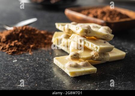 White nutty chocolate with hazelnuts on black table. Stock Photo