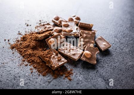 Nutty chocolate with hazelnuts and cocoa powder on black table. Stock Photo
