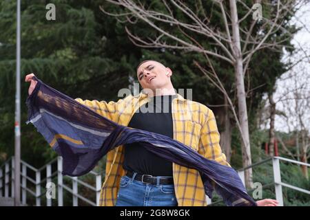 Young non binary person dancing and singing in the street. Make up androgynous person. Stock Photo