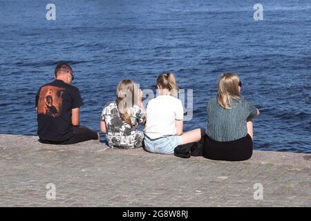 Stockholm, Sweden - July 21, 2021: A family is sitting on the quayside. Stock Photo