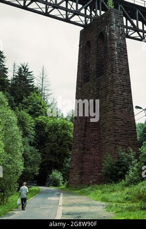 man walking under the old rail bridge, stone railway viaduct from below Stock Photo