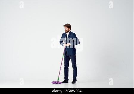 business man in a suit with a mop in his hands providing services cleaning floors Stock Photo