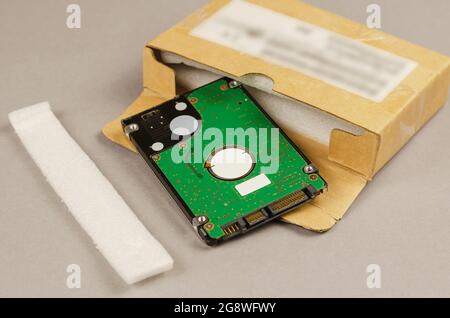 Brown cardboard box and internal computer hard drive on gray background. Open postage package and Device used to store digital content and other perso Stock Photo