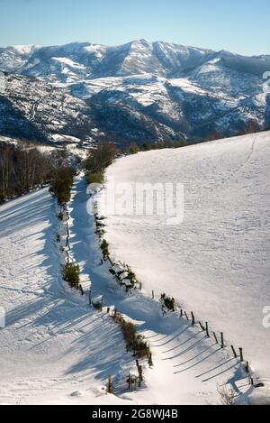 Snowy landscape with a path between fields and mountains in the background in Seoane do Courel Galicia Stock Photo