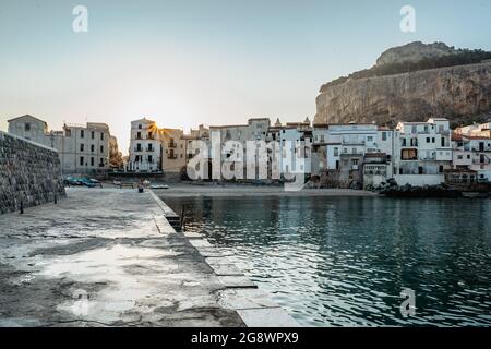 Sunrise on beach in Cefalu, Sicily, Italy, old town panoramic view with colorful waterfront houses, sea and La Rocca cliff.Attractive summer cityscape Stock Photo