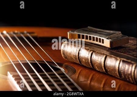 vintage wooden harmonica lying on an old acoustic guitar. Stock Photo