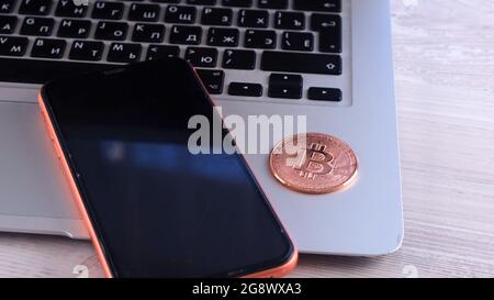 Golden bitcoin on the desk with laptop and smartphone. Crypto is Digital Money within the blockchain network, is exchanged using technology and online Stock Photo