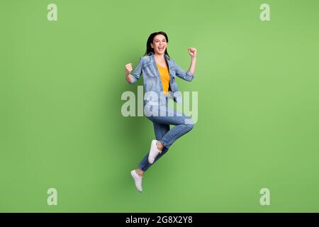 Full size profile photo of hooray brown hairdo lady jump wear jeans shirt sneakers isolated on green background Stock Photo
