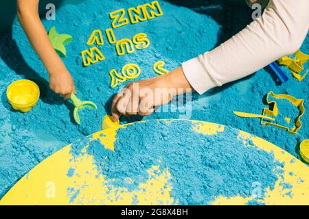 Children's and adult hands playing with blue kinetic sand. Art therapy.  Relieving stress and tension. Tactile sensations. Development of fine motor  Stock Photo - Alamy