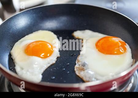 Breakfast getting ready. Sunny side fried eggs on the pan, closeup. Stock Photo