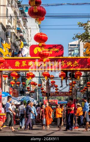 Buddhist monks on busy street in downtown Yangon decorated with red chinese lanterns in preparation for Chinese New Year celebrations Myanmar Stock Photo