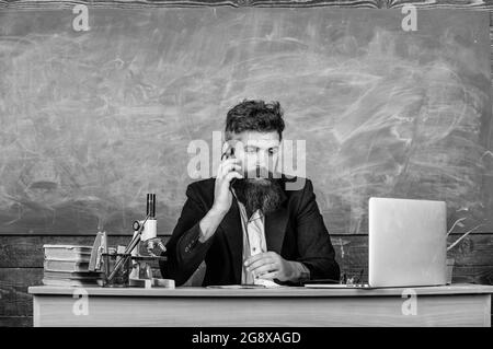 School principal or teacher calling parents to report about exam results. School teacher cares about communication with parents. Man with beard talk Stock Photo