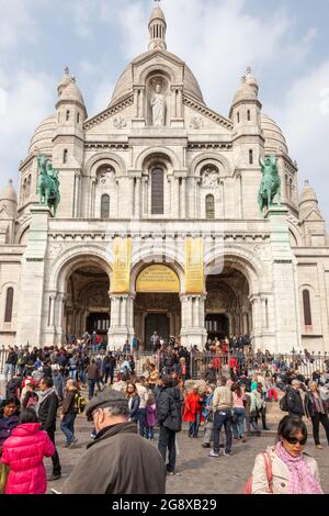 Crowd of tourists gathered at the foot of the Basilica of the Sacred Heart of Montmartre, in Paris Stock Photo