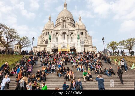 Crowd of tourists gathered at the foot of the Basilica of the Sacred Heart of Montmartre, in Paris Stock Photo