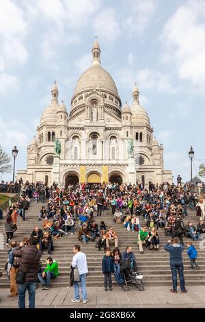 Crowd of tourists gathered at the foot of the Basilica of the Sacred Heart of Montmartre, in Paris Stock Photo