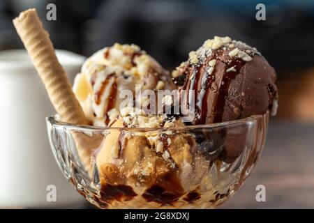 Chocolate, cream and caramel Roma ice cream in a glass bowl with hazelnut and chocolate sauce poured over it. Stock Photo