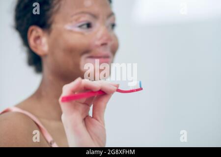 Young dark-skinned woman brushing her teeth and smiling Stock Photo