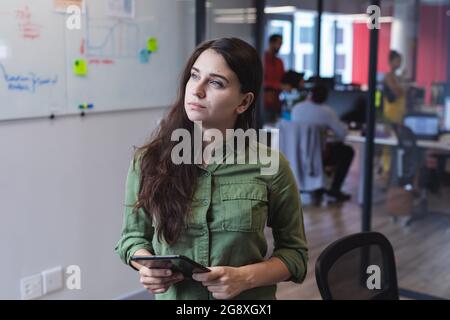 Caucasian female creative worker using tablet computer and looking away Stock Photo