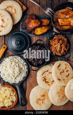 Table served with Venezuelan breakfast, arepas with different types of fillings such as caraotas, carne mechada, pernil , fried plantain and cheese Stock Photo