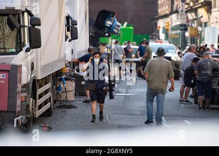 Glasgow, Scotland, UK. 22 July 2021.  PICTURED: A film crew member walks with a pump action shot gun film prop. Filming on the set of the new Indiana Jones 5 movie in the middle of Glasgow city centre has moved to the Merchant city district as the Hollywood blockbuster sets up Glasgow as 1950s/1960s America.  Film cast, lead and supporting actors with extras along with the productions crew, and directors and runners can be seen on and off set. Credit: Colin Fisher Stock Photo