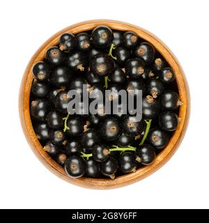 Blackcurrant berries, in a wooden bowl. Fresh, ripe black currant berries, also known as cassis, spherical edible fruits of Ribes nigrum. Stock Photo