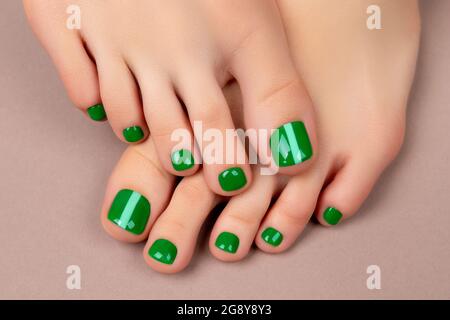 Womans feet with green nail polish on brown background Stock Photo