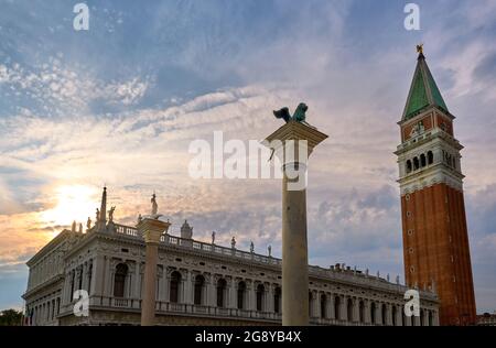 Icons of Venice, Italy: St Mark lion and St Theodore columns in piazzetta on St Mark square. Campanile of St Mark and Biblioteca Marciana. Stock Photo