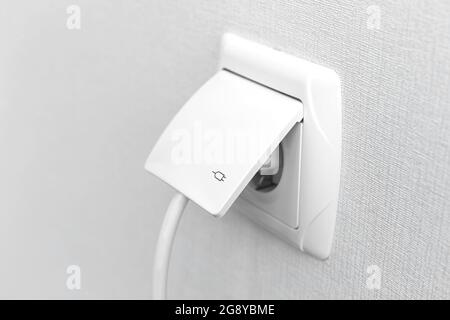 White plug into electric socket, modern interior Stock Photo