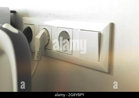 Kitchen electricity concept background with electric outlet on wall and electric kettle plugging in Stock Photo