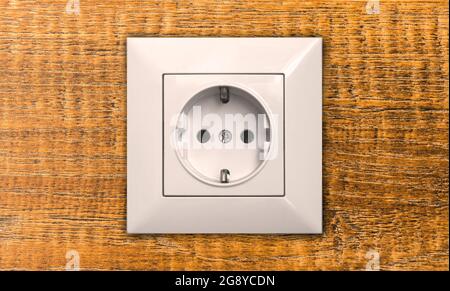 Electric outlet on wooden wall in house interior close-up, EU socket Stock Photo