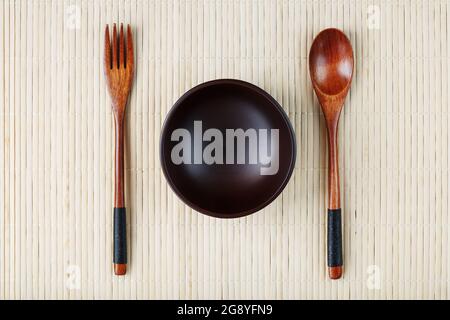Wooden Spoon, Fork and Plate on a Bamboo Backing. Asian food handicraft concept. View from above Stock Photo