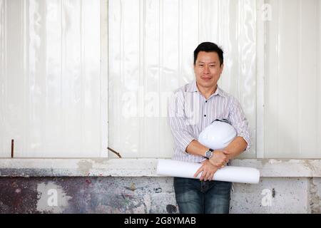 Portrait of male engineer with self-confidense and friendly manner, holding roll paper Stock Photo