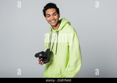 smiling african american guy with vintage camera holding hand in pocket isolated on grey Stock Photo