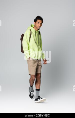 african american man in green hoodie standing with hand in pocket of beige shorts isolated on grey Stock Photo