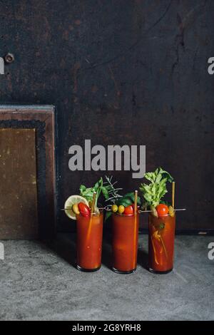 three Bloody Mary cocktails in a row on concrete floor Stock Photo