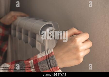 Woman hand adjusting radiator thermostat at home, using a regulator at winter background photo Stock Photo