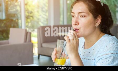 Attractive young lady drinks juice in cafe, side view Stock Photo