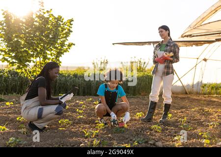Girl planting by mother and female farmer at organic farm Stock Photo