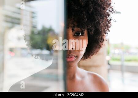 Young woman standing behind glass Stock Photo