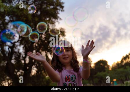 Girl playing with soap bubbles during sunset Stock Photo