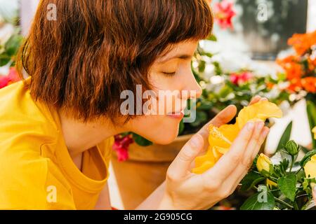 Woman smelling Hibiscus flower in home garden Stock Photo