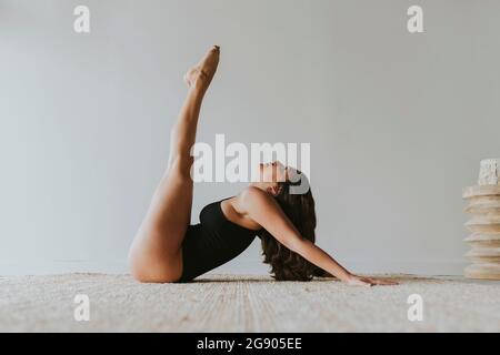 Flexible yogi with feet up practicing yoga at health club Stock Photo