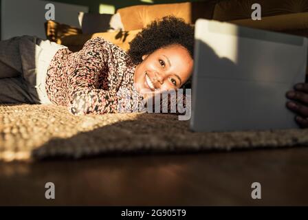 Woman smiling while using digital tablet at home Stock Photo